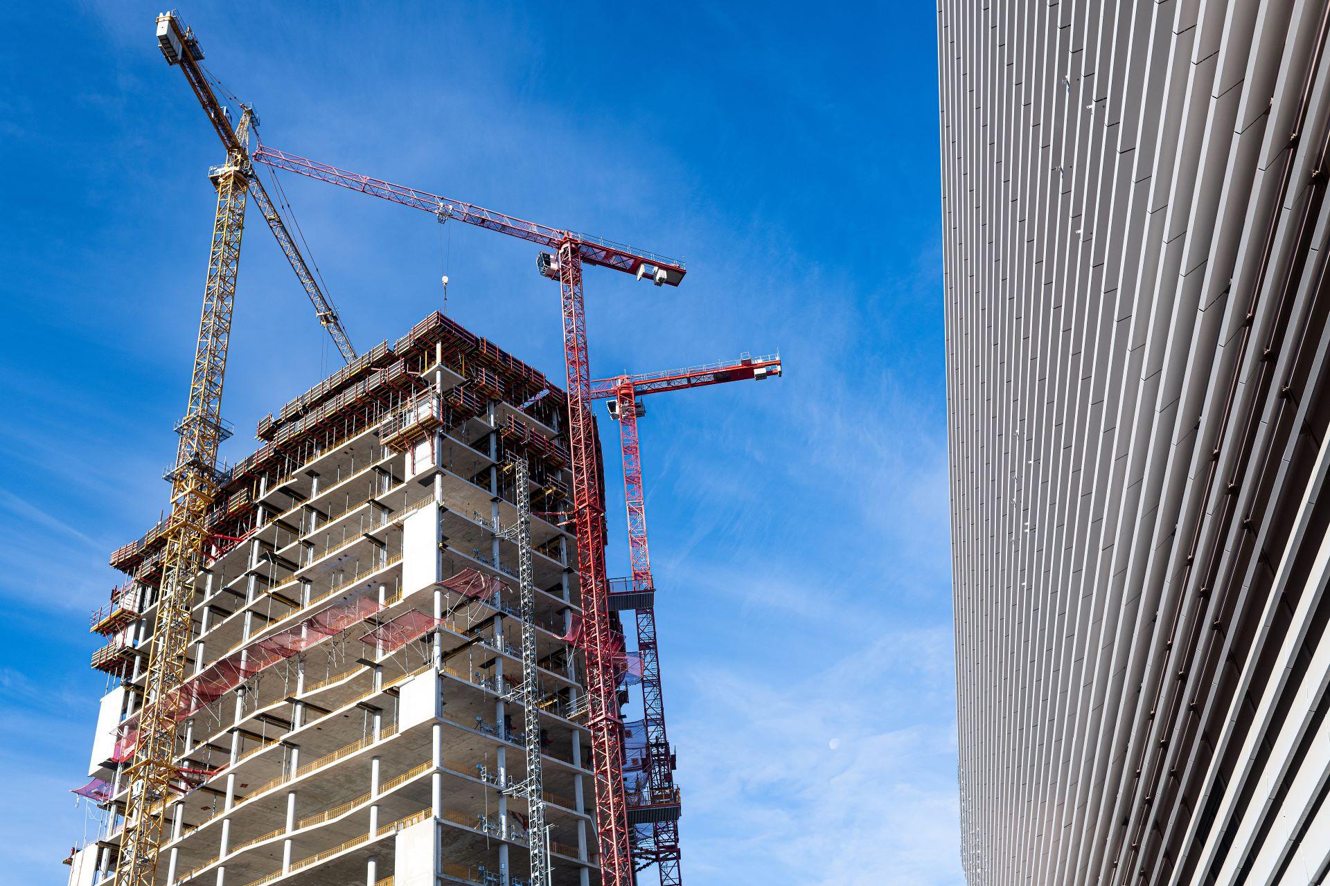 Baustelle in Berlin mit Wolkenkratzern, Kränen und blauem Himmel